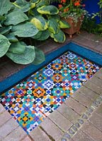 Mosaic lined Moroccan style pool surrounded by Hosta in a small town garden - Brighton, UK 