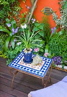 Mosaic Moroccan table in small garden with painted walls and decking, Brighton, UK 