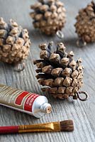 Step by step of making Christmas Doorknob Decorations - Apply gold paint to the outside of the fir cones with a dry brush and leave to dry