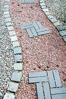 Attractive garden path made of ornamental gravel cobble setts and blue slate bricks
