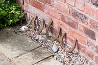 Old horseshoes against red brick wall by stone path