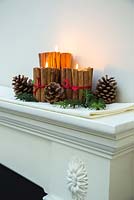 Christmas candle decorations made using cinnamon sticks and ribbon