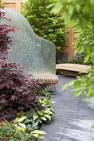 The SeeAbility Garden, Chelsea Flower Show 2013. View of seating areas with Acer 'Bloodgood' and Hosta 'June' with Hornbeam tree in background.