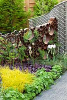 The SeeAbility Garden, foliage based perennial border with corten steel circle sculpture and stainless steel ball structure