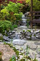 A stream and waterfall flowing beside a traditional Japanese tatami room in the 'An Alcove - Tokonoma Garden' 