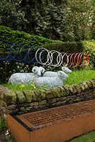 Le Jardin de Yorkshire garden - wire mesh sheep and bicycle wheel sculpture, dry stone wall and corten rusted steel water trough 