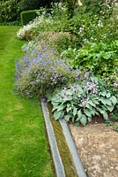 A simple rill runs alongside the herbaceous border, including glaucous hostas and geraniums. 