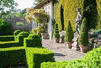 Box parterre with Casita beyond and Italian marble statue of youth against the yew hedge.