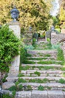 Stone steps link terracing on the steep site, framed with clipped rosemary bushes. 