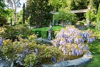 Lily pool surrounded by wisteria with 16th century figure of a huntsman as fountain. 