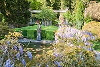 Lily pool surrounded by wisteria with 16th century figure of a huntsman as fountain.