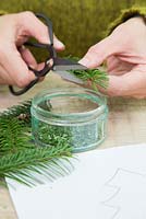 Trimming christmas tree branch into small cuttings.