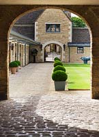 View through to the stable courtyard with box balls in metal containers and lawn