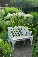 White metal seat in well garden with Hydrangea arborescens 'Annabelle'. Behind is Phlomis russeliana and to the right is Hemerocallis 'Green Flutter'