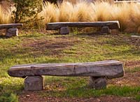 A circle of wooden benches by Marc Nucera in woodland with Stipa tenuissima. Provence, France, Domaine de la Verriere
