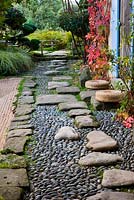 Japanese style garden - view to the east side of the house with blue shutters, path with pebbles and rocks and gravel garden
