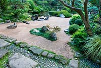 The zen meditation gravel garden with rocks, raked gravel, pool, crane island on left, turtle island on right with Cotoneaster horizontalis