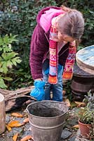 Young girl extinguishing a used sparkler in a bucket of water. Set within an autumnal back garden.
