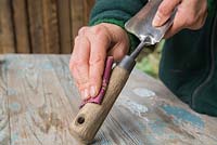 Sanding down wooden parts of trowel to remove any splinters and prepare for oiling