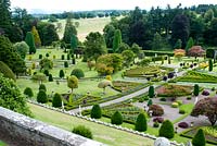 Looking over the balustrade at the stunning grand parterre garden with Buxus edged beds shaped like great fans or triangles and the whole garden studded with shaped colourful trees and topiary intermingled with statues 