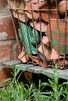 An old wire shopping basket with broken terracotta in a small town garden
