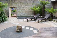 Japanese style courtyard garden beside the house features contrasting surfaces, tree ferns and outdoor furniture by Gloster.