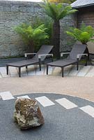 Japanese style courtyard garden beside the house features contrasting surfaces, tree ferns, aspidistras and outdoor furniture by Gloster. 