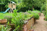 Climbing frame with herb bed in foreground planted with chives