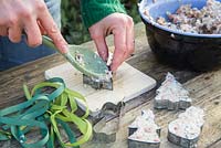 Filling cutters with mixture - making cookie cutter and pine cone bird feeders