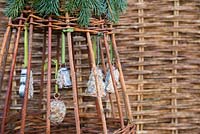 Cookie cutter and pine cone bird feeders hanging from woven wigwam