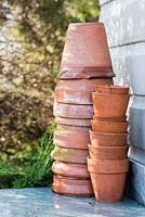 Collection of Terracotta pots on a potting bench, beside a shed with dappled lighting