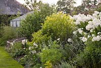 Greenhouse nestled among Summer planting including Phlox