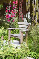 Seating area with a Leather appliqué backdrop displaying Magnolias, Foxgloves and Iris. Deschampsia cespitosa. Fresh Garden: The Massachusetts Garden. 