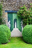 Trompe l'oeil - mural next to Buxus sempervirens and Honeysuckle - The West Garden, Daglingworth House, Gloucestershire, UK. June. 