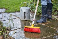 Cleaning patio with soapy water and brush
