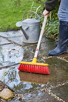 Cleaning patio with soapy water and brush