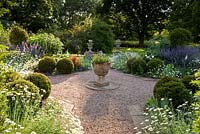 Cothay Manor, Greenham, Somerset. Herbaceous borders with gravel path and stone urn centrepiece