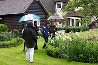 Visitors in an open National Gardens Scheme garden, in heavy rain