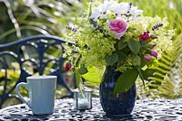 Flower arrangements with roses, Alchemilla mollis, lavender and daisies in blue vase