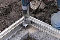 Greenhouse construction - fixing aluminium base down securely onto concrete blocks 