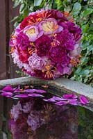 Peony sphere with honeysuckle  on a granite water trough -  varieties are e.g. 'Karl Rosenfeld', 'Auguste Dessert', 'Bowl of Beauty' and 'Bunker Hill'