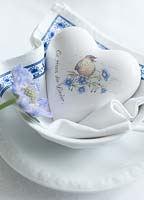 Decorative ceramic heart bedded on napkin in a bowl with Scabiosa blossom