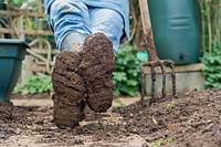 Gardener resting wearing muddy boots after digging the garden