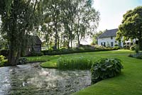 View of the garden with pond and large lawn area. De Carishof