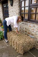 Growing strawberries and nasturtiums in a straw bale - using a bread knife to create a hole for planting