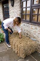 Growing strawberries and nasturtiums in a straw bale: use a bread knife to create a hole for planting