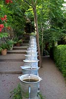 Water display consisting of a series of galvanised buckets running alongside a set of steps. Jardins des Paradis, Cordes-sur-Ciel, Tarn, France, designed to encourage children's interest in gardening. 