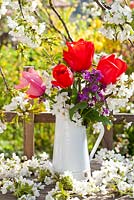 Floral display of spring flowers includes tulips, honesty and cherry.