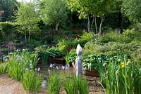 A Garden for First Touch at St George's Sloping garden of green foliage especially hostas and Siberian Iris with stepped water course in rusty steel channel. 