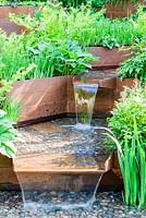 A Garden for First Touch at St Georges: Detail of stream contained by corton steel sides with hostas, ferns and iris - Designer: Patrick CollinsSponsors: St Georges Hospital and Medical School, Tendercare, Landscape Associates2014 RHS  Chelsea Flower Show garden awarded Silver Gilt medal